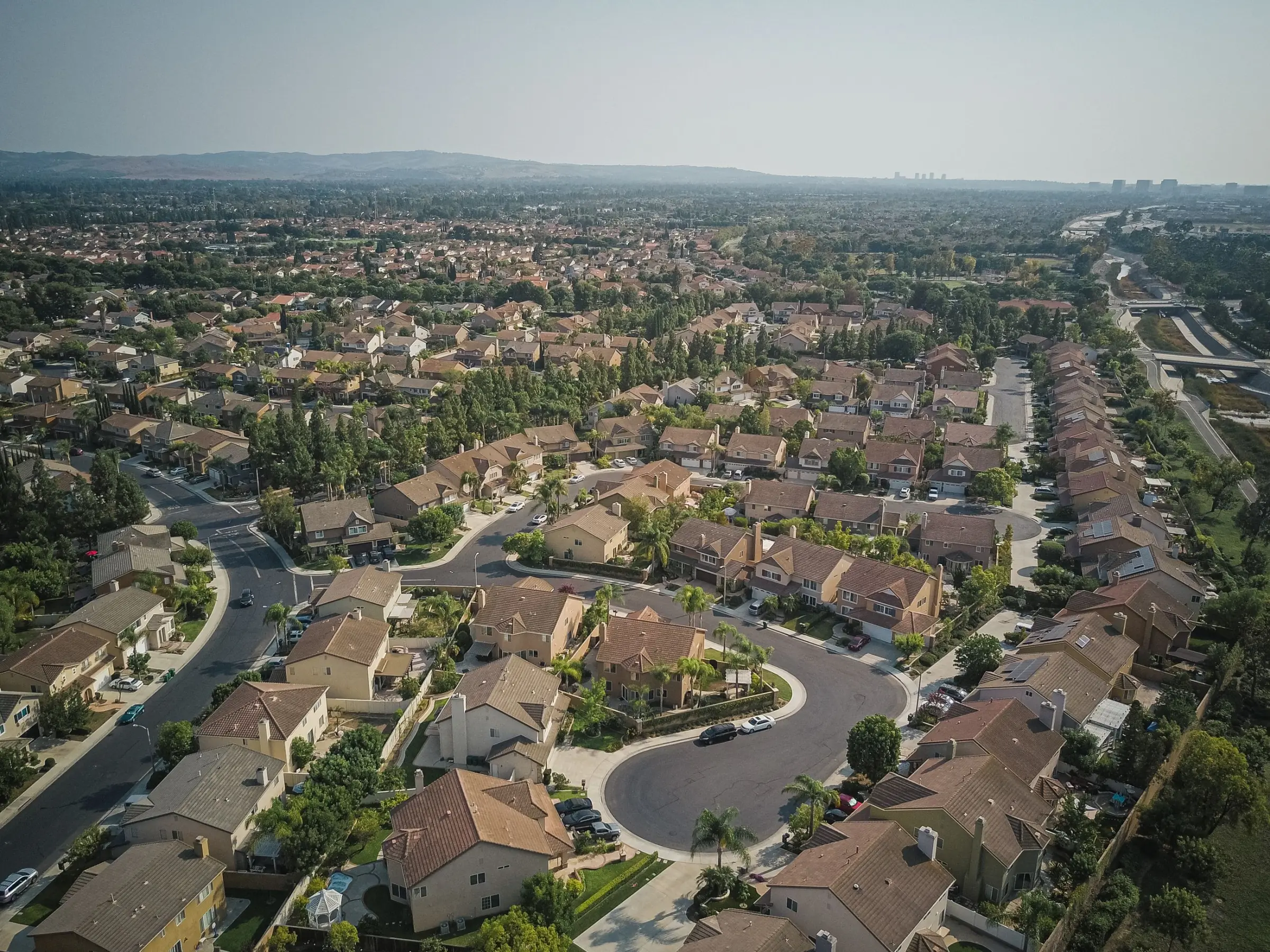 A Texas neighborhood seen from above, with cul-de-sacs, tiled roofs and palm trees